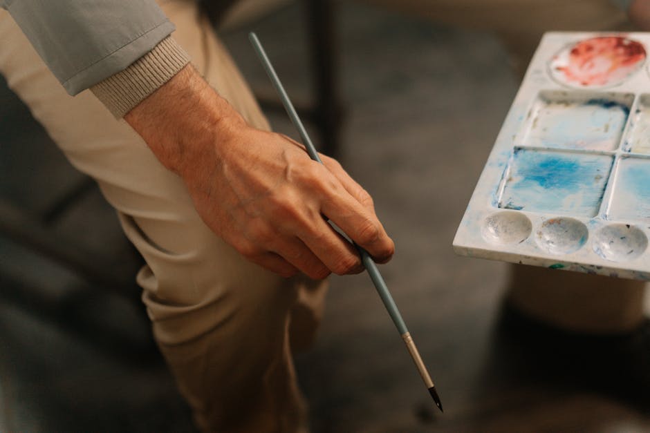 Close-up of an artist holding a paintbrush and palette, perfect for creative themes.